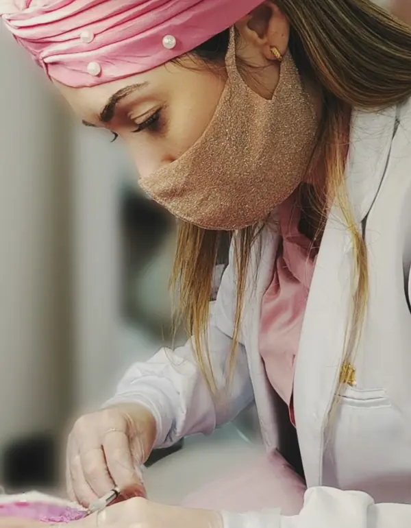 A Dra. Gabriela de máscara e touca rosa, concentrada no procedimento